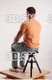 Sitting pose orange thsirt light blue jeans of bodybuilder Harold…